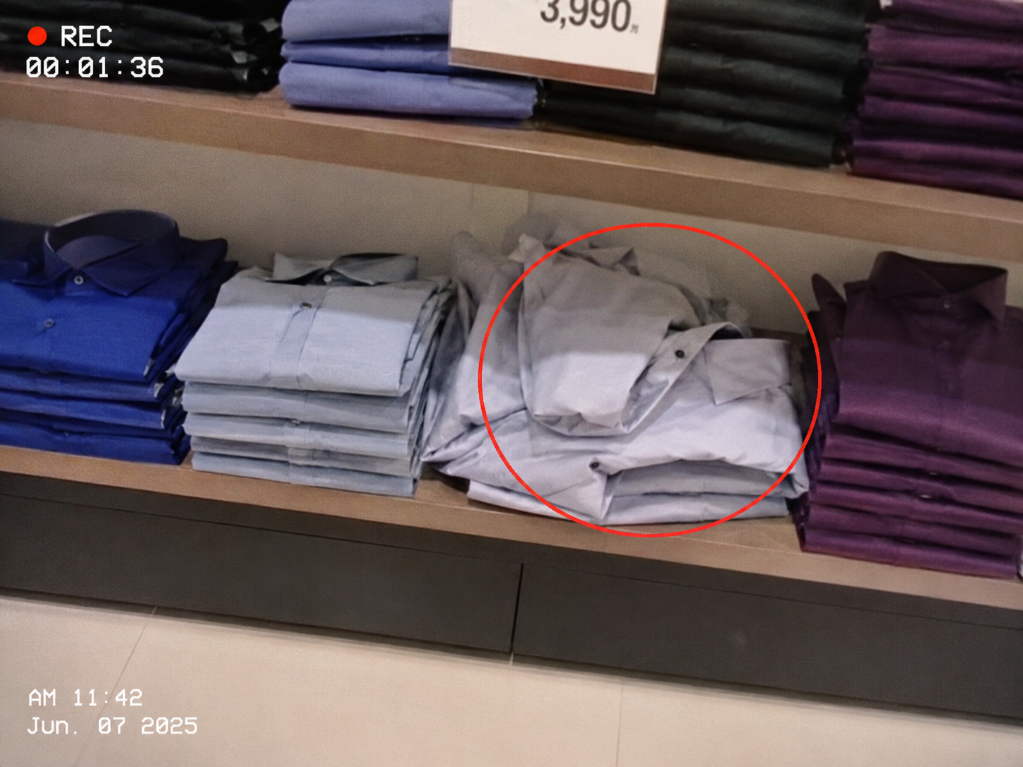 Anonymised retail merchandising image showing disorganised folded shirts